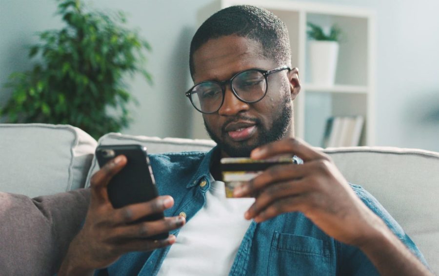 A man hold a credit card while using a cell phone