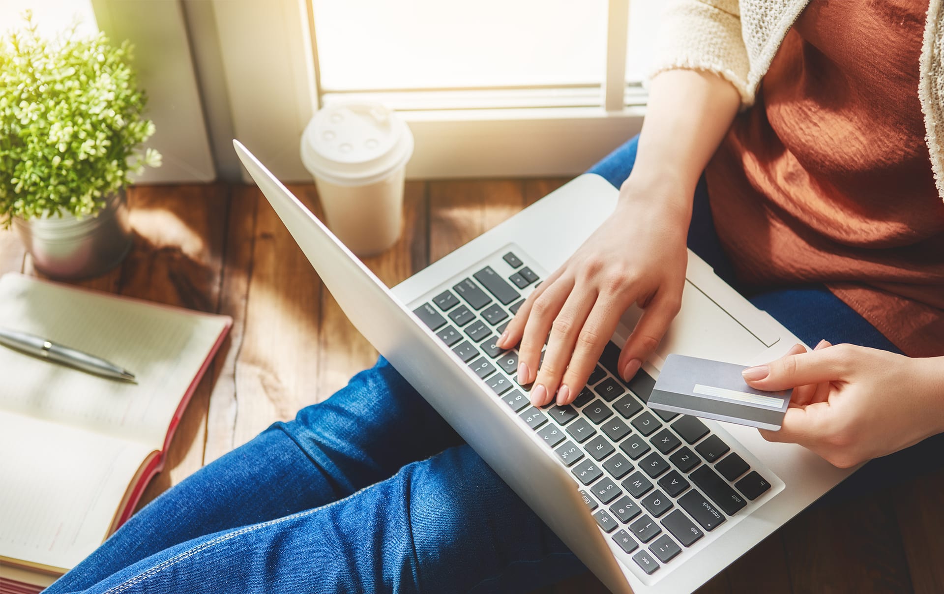 A person hold a credit card while using a laptop