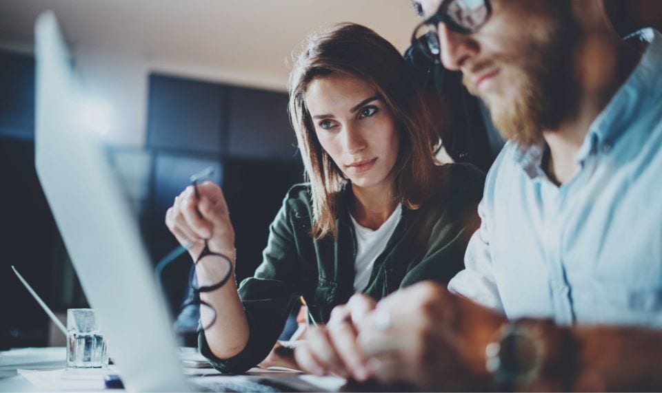 a man and a woman are studying something on a computer screen