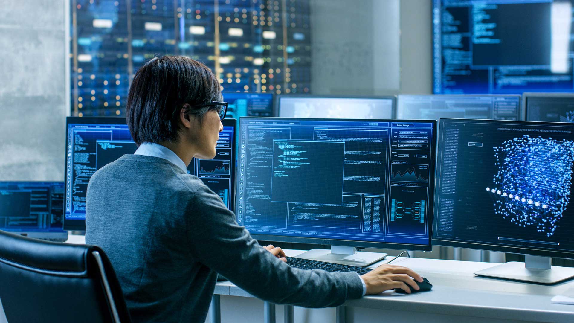 man sits at a desk with two computer monitors